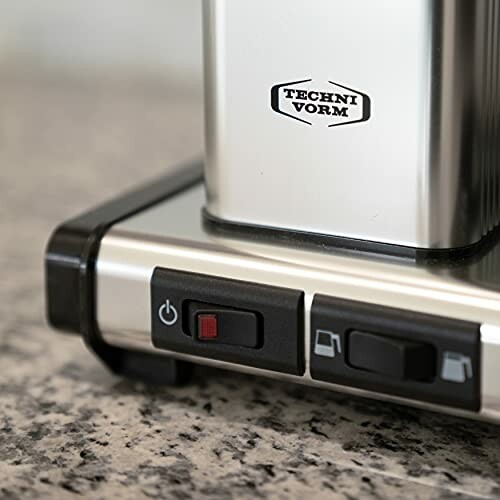 Close-up of a coffee maker base with control buttons on a countertop.