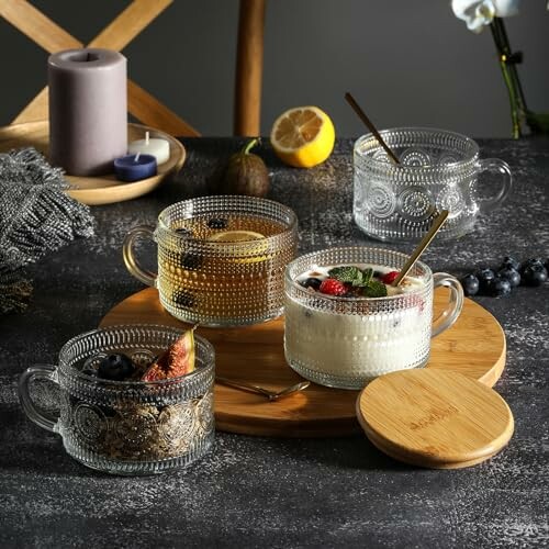 Elegant glass cups with various desserts and tea on a dark table.