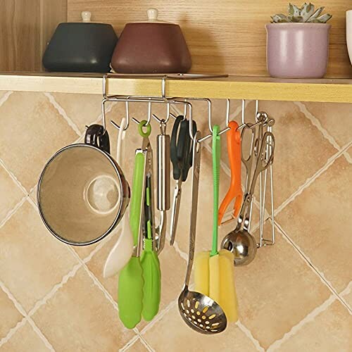 Kitchen utensils hanging on a rack under a shelf.