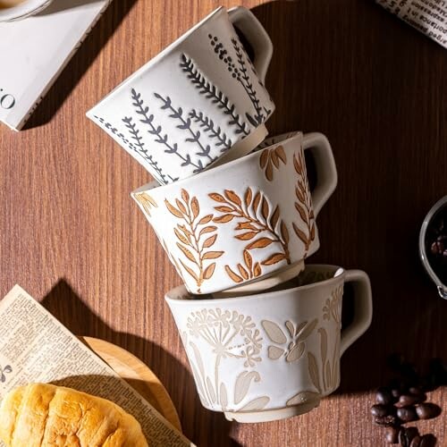 Three stacked ceramic cups with floral designs on a wooden table